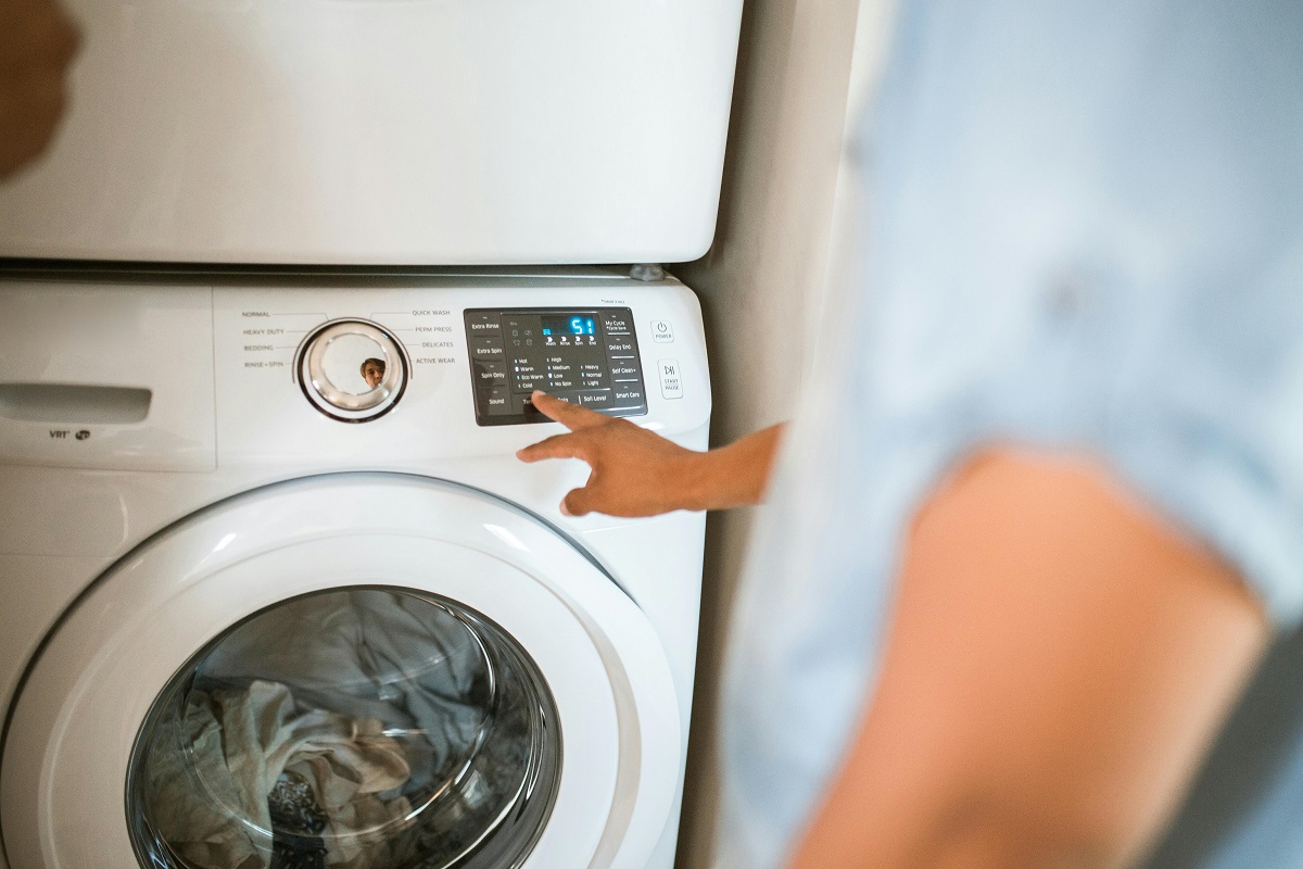 woman pressing buttons on a washing machine control panel